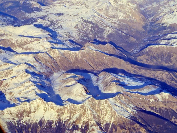 Nice, France, December 18, 2024. Suggestive view from the plane of the reliefs of the French Alps whitened by snow. The mountains and valleys appear devoid of vegetation. The French Alps are located a short distance from the French Riviera with Nice and after the small strip of the Prealps.