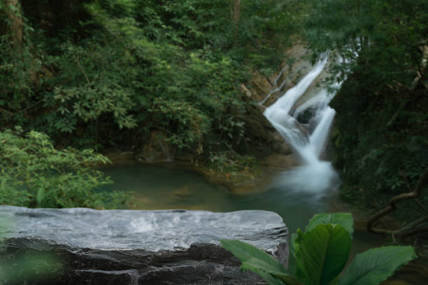 Grey stone table top podium with outdoor waterfall fresh green tropical forest nature background landscape.Natural water or mineral product present placement pedestal rock stand display.