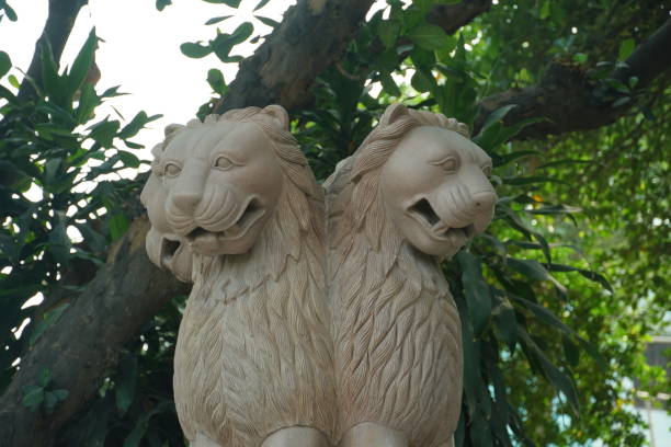 stone statue of lion capital with lush greenery background