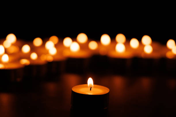 istock Illuminated single candle with blurred background candles in dark 2192975163