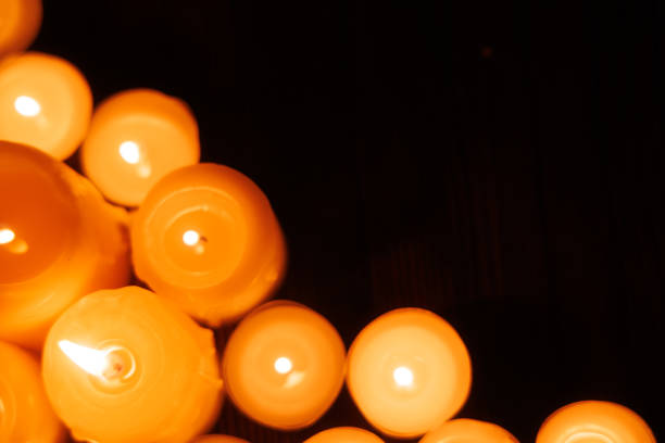 istock Large candle surrounded by small burning candles on black background, top view. Easter symbol of light and faith 2192975381
