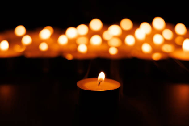 istock Lit candle symbolizing prayer with glowing candles in darkness 2192975419