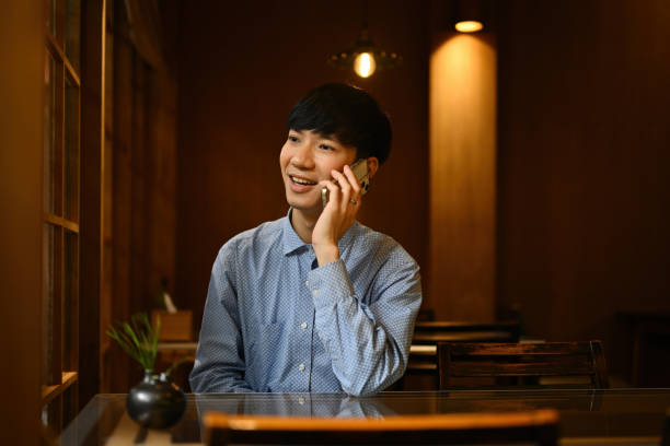 istock Young Businessman call with a cell phone while sitting alone in the restaurant during free time, having a talking conversation with mobile phone 2192975442