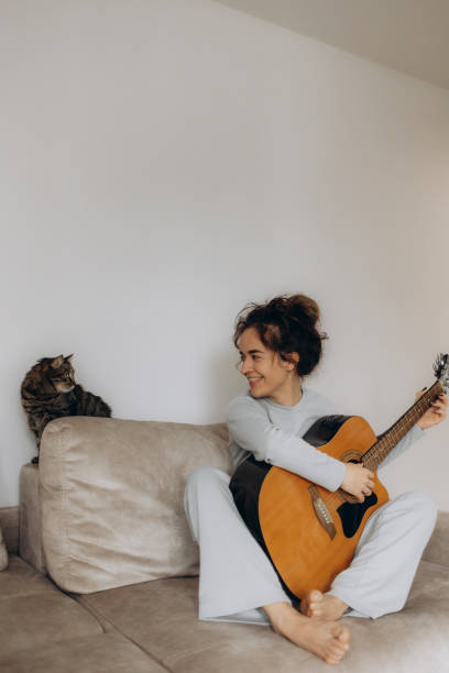 istock a woman plays guitar for a cat at home 2192978318
