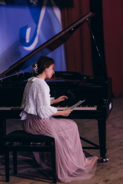 istock Young woman practicing piano at home and reading sheet music 2192978320