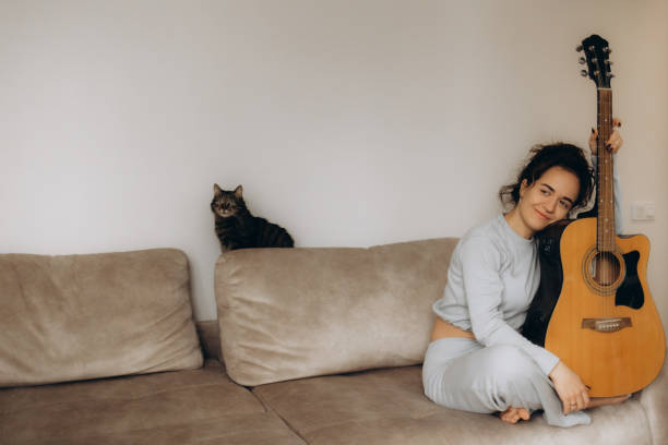 istock a woman plays guitar for a cat at home 2192978323