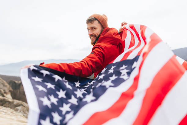 istock Cheerful man with American flag waving in the wind 2192990138