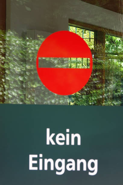 Glass door with the words 'kein Eingang' (German: no Entrance). In the glass is a garden reflected