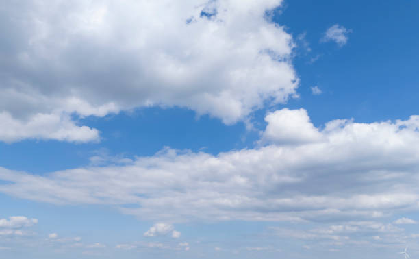 A clear blue sky filled with fluffy white clouds, perfect for tranquil backgrounds or nature-themed projects.