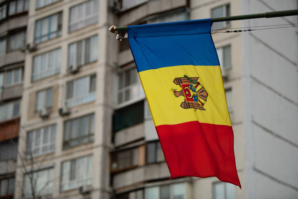 A vibrant Moldovan flag displays its traditional colors as it flutters against the backdrop of an urban apartment building in Chisinau, capturing the national pride.
