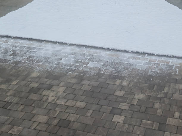 A close-up view of freshly fallen snow on pavement, highlighting the contrast between white snow and dark stone tiles. Perfect for seasonal themes.