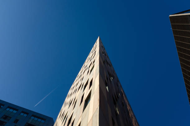 Low angle view of a modern building reaching into a clear blue sky, showcasing architectural design and urban landscape