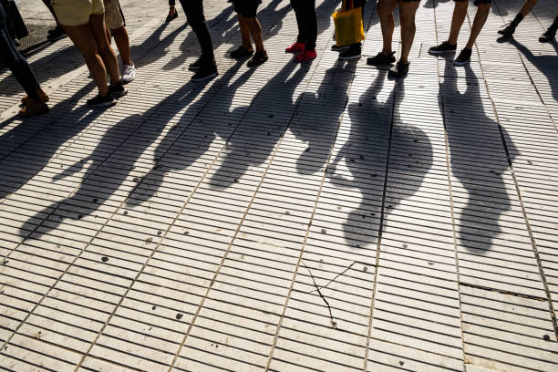 istock People on a sidewalk with shadows cast on the ground 2192997081