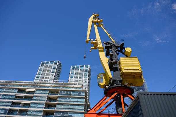 In front of a very tall building, there stands a bright yellow crane that is utilized for construction work, showcasing its engineering prowess