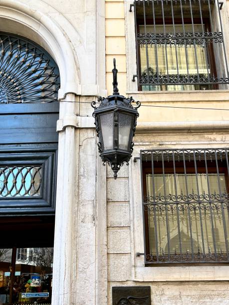 Venice, Italy - February 13, 2024: Ornate wrought iron lantern hangs gracefully against the textured facade of a Venetian building, adding a touch of classic elegance to the urban scene in Venice, Italy