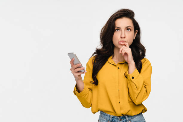 istock Thoughtful dreaming woman holding using smart phone looking up isolated over white background 2193010632