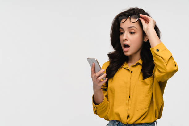 istock Amazed shocked surprised woman holds smartphone looking at screen standing Isolated white background 2193010690