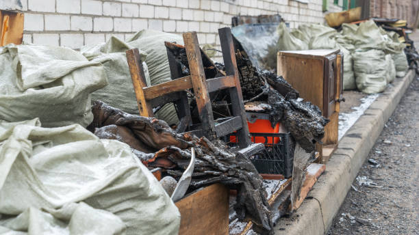 A private home stands in ruins after a devastating fire, with charred belongings scattered on the street. The scene reflects the aftermath of destruction and loss, evoking deep emotions.