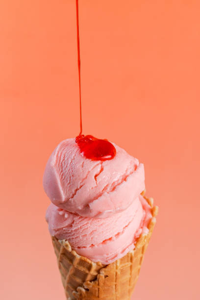 istock Strawberry ice cream in a cone, with syrup dripping, on a minimalist red background 2193017126