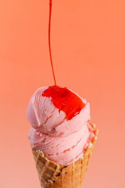 istock Strawberry ice cream in a cone, with syrup dripping, on a minimalist red background 2193017134