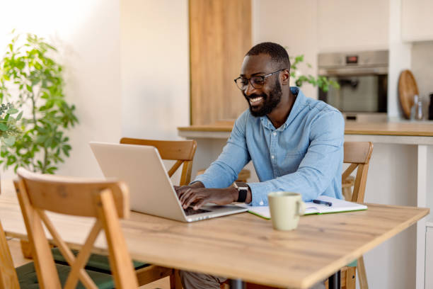 istock Young black man working from home smiling and typing on his laptop 2193017303