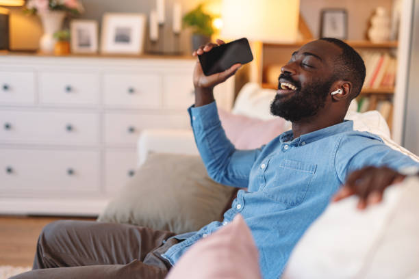 Young man relaxing on sofa listening to music and singing