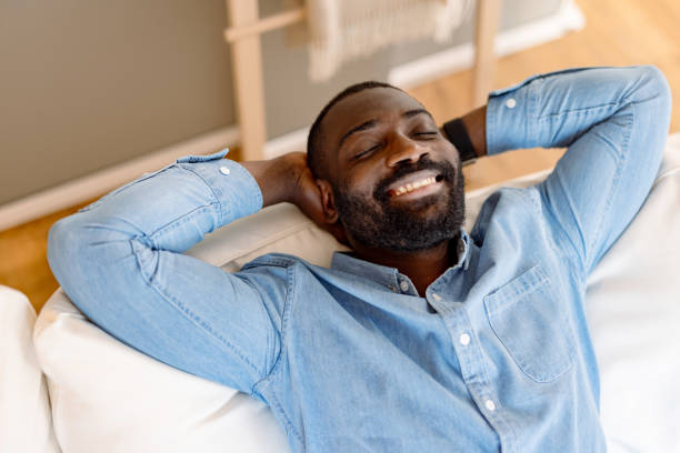 istock Relaxed man lying on sofa with hands behind head smiling 2193017412