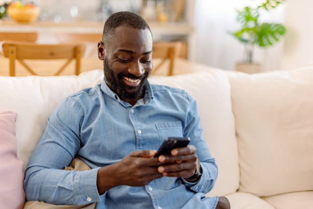 istock Happy man using mobile phone sitting on sofa at home 2193017420