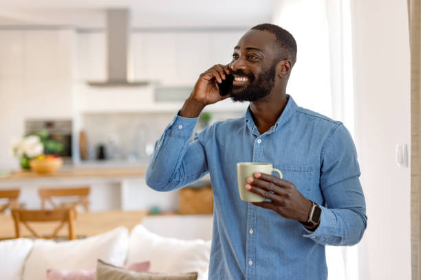 istock Happy man talking on phone and drinking coffee at home 2193017452