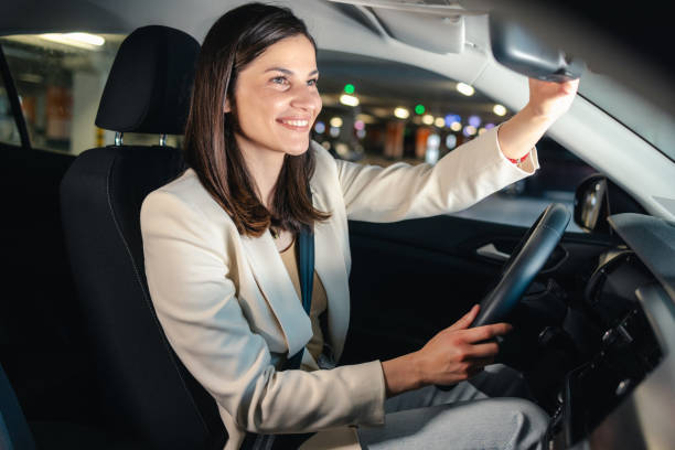 istock Confident woman adjusting rearview mirror while driving car in parking garage 2193020309