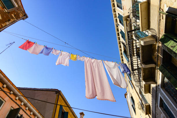 Venice, Italy - July 3, 2022: Typical city corner with ancient colorful buildings Drying clothes on a clothes-line in outdoor at sunny summer day. Venice, Italy