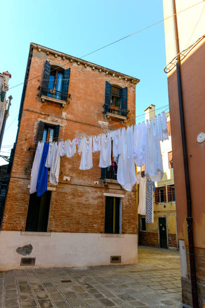 Venice, Italy - July 3, 2022: Typical city corner with ancient colorful buildings Drying clothes on a clothes-line in outdoor at sunny summer day. Venice, Italy