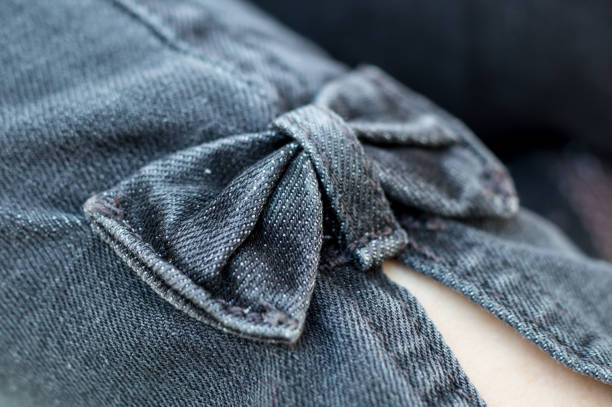 Macrofotografía detalle de un lazo en la pierna de unos pantalones vaqueros
