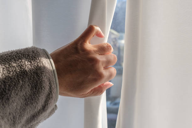 istock A woman’s hand opening a window curtain. 2193031139