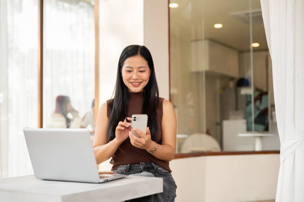 istock A satisfied Asian woman checks messages on her smartphone while working remotely from a coffee shop. 2193038679