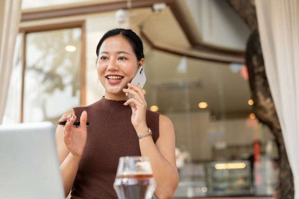 istock A beautiful, confident Asian woman talks in the phone while working remotely from a cafe. 2193038683
