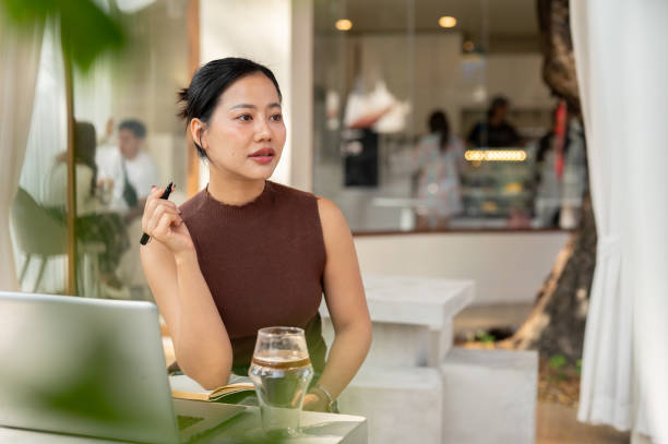 istock A thoughtful Asian woman looks away, pondering something while working remotely from a cafe. 2193038729
