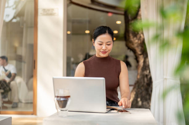 istock A satisfied Asian woman checks messages on her smartphone while working remotely from a coffee shop. 2193038774