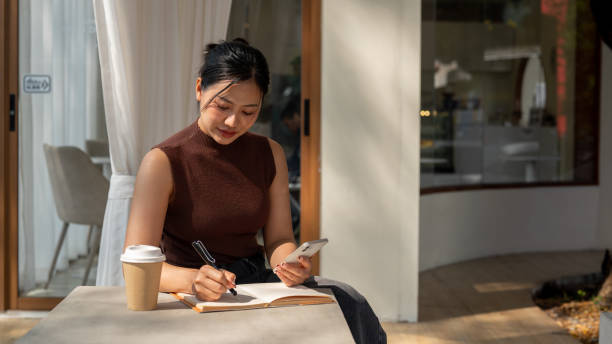 istock An attractive Asian woman takes notes in a book or writes in her diary while relaxing in a cafe. 2193038972