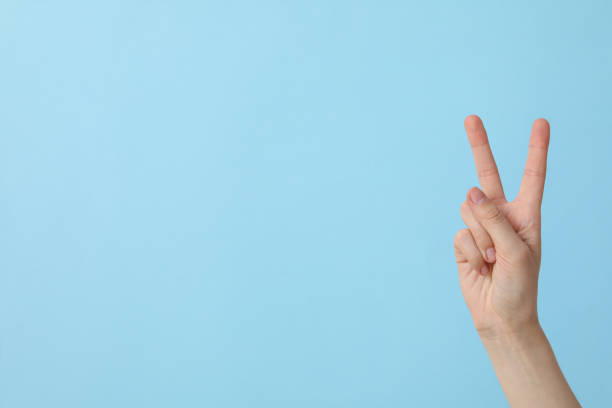 istock Female hand showing two fingers on a blue background, place for text 2193038987