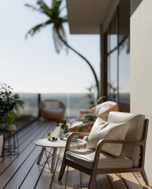 A minimalist comfortable armchair with a pillow placed on a balcony with a stunning beach view.