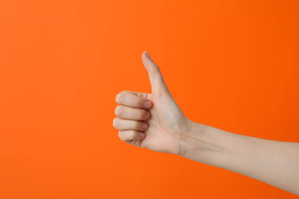 istock Female hand showing thumb up on orange background 2193039549