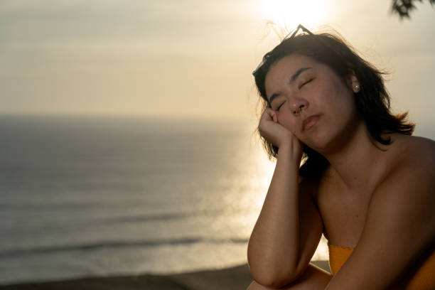 istock Young woman relaxing by the sea at sunset after work 2193040659
