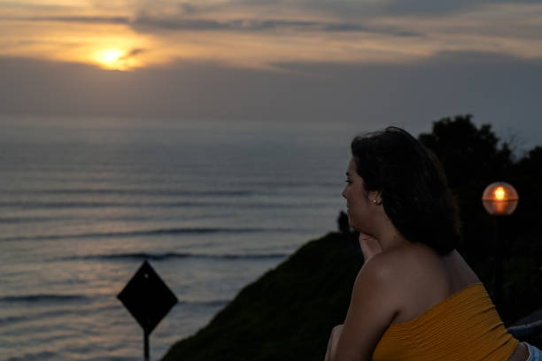 istock Young woman meditating by the ocean at sunset after work 2193040767