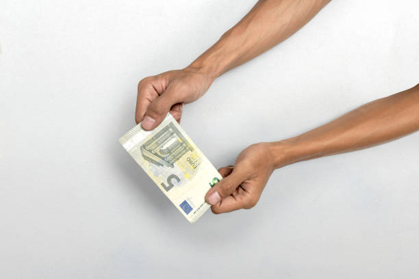 Human hand giving five euro banknote cash on white background. Finance and European currency concept