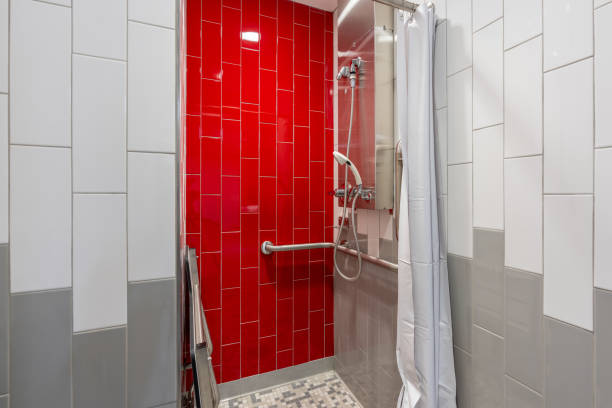 istock New single, private, gym locker room shower with red tile wall, bench, tile floor, and white shower curtain. 2193044824
