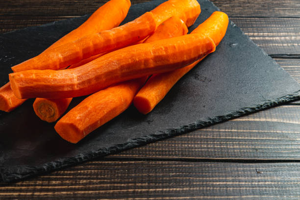 Washed fresh carrots on a stone board on a wooden table High quality photo.