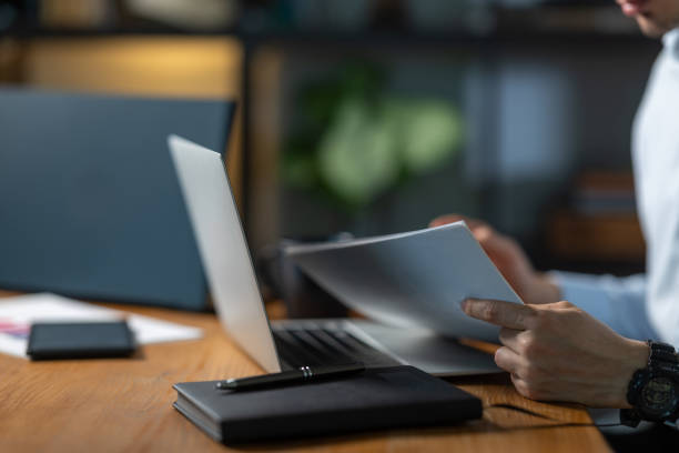istock Businessman reading documents at office desk with laptop 2193047588