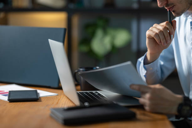istock Businessman reading documents and thinking in office at night 2193047611