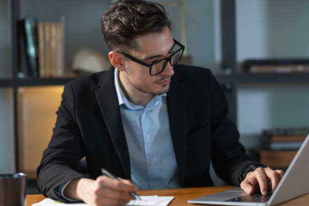 istock Focused businessman working with laptop and taking notes in modern office 2193047658